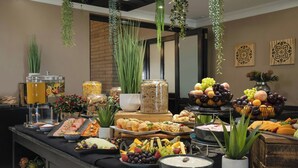 Un buffet proposant une variété de plats et de boissons, notamment des fruits, des fromages et des pâtisseries.