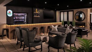 Un espace bar moderne agrémenté d’une enseigne Heineken, d’un téléviseur et d’une cheminée.