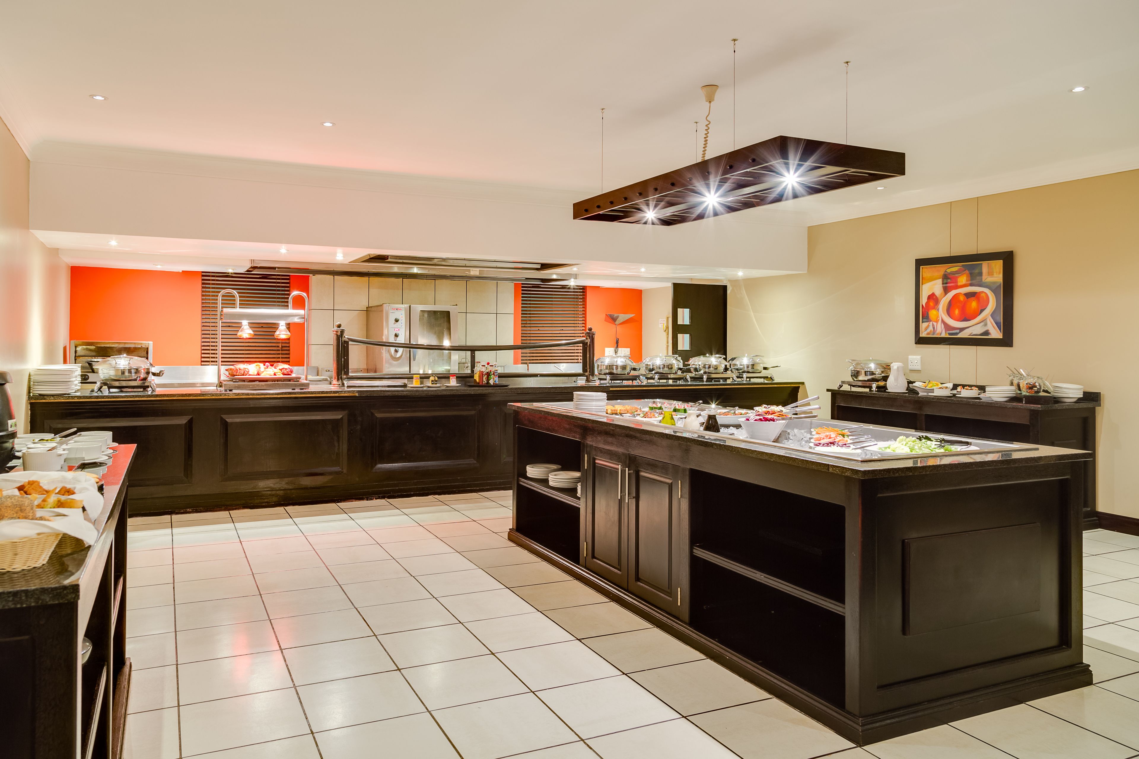 A modern kitchen with a central island, equipped with various appliances and a buffet setup.