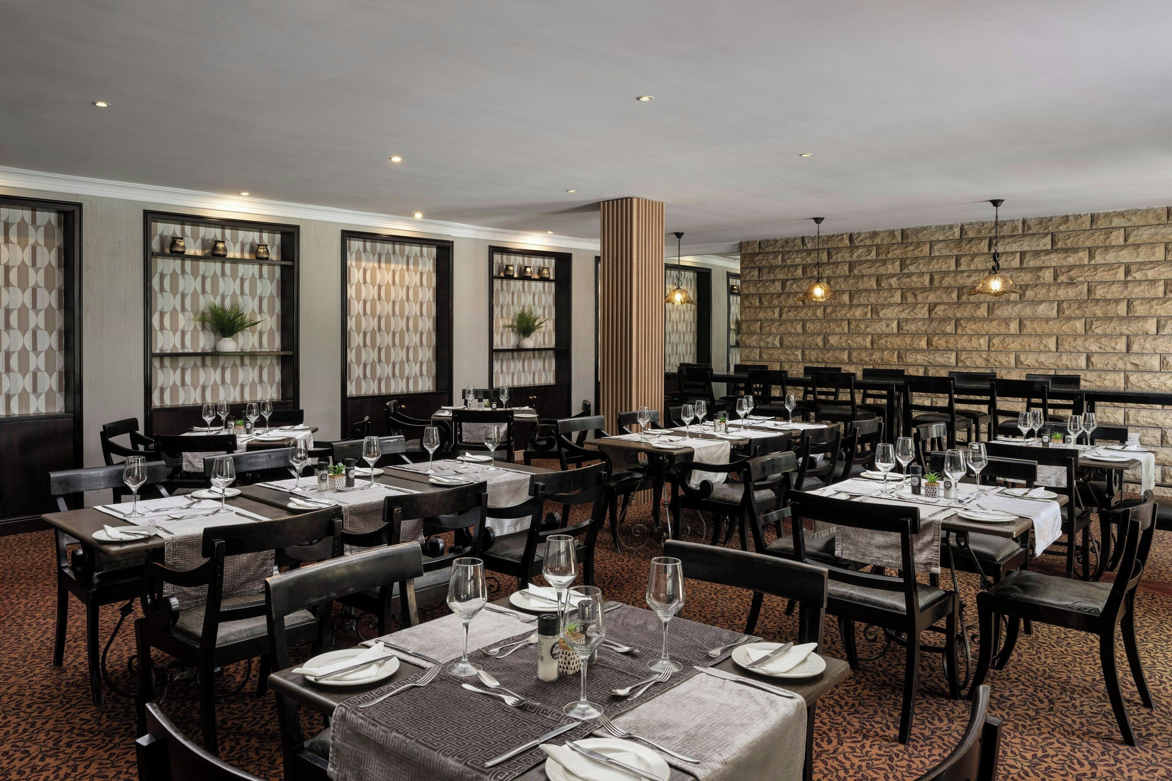 A restaurant with multiple tables set for dining, featuring a patterned wall and a stone accent wall.