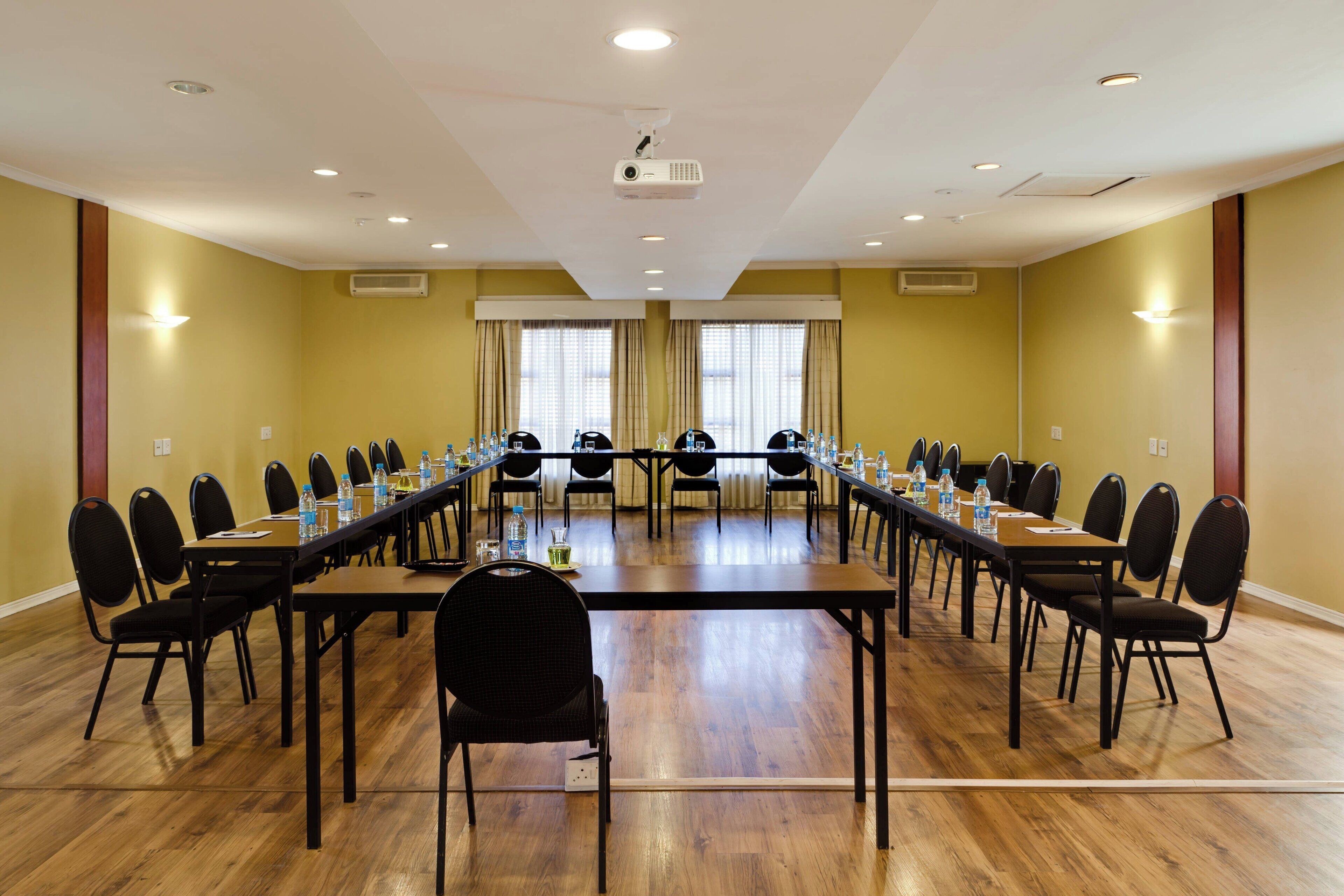 Un salón de conferencias con una larga mesa, sillas y un proyector.