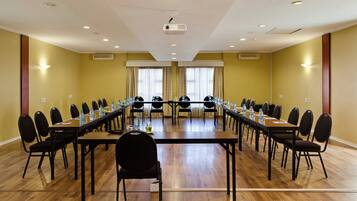 Un salón de conferencias con una larga mesa, sillas y un proyector.