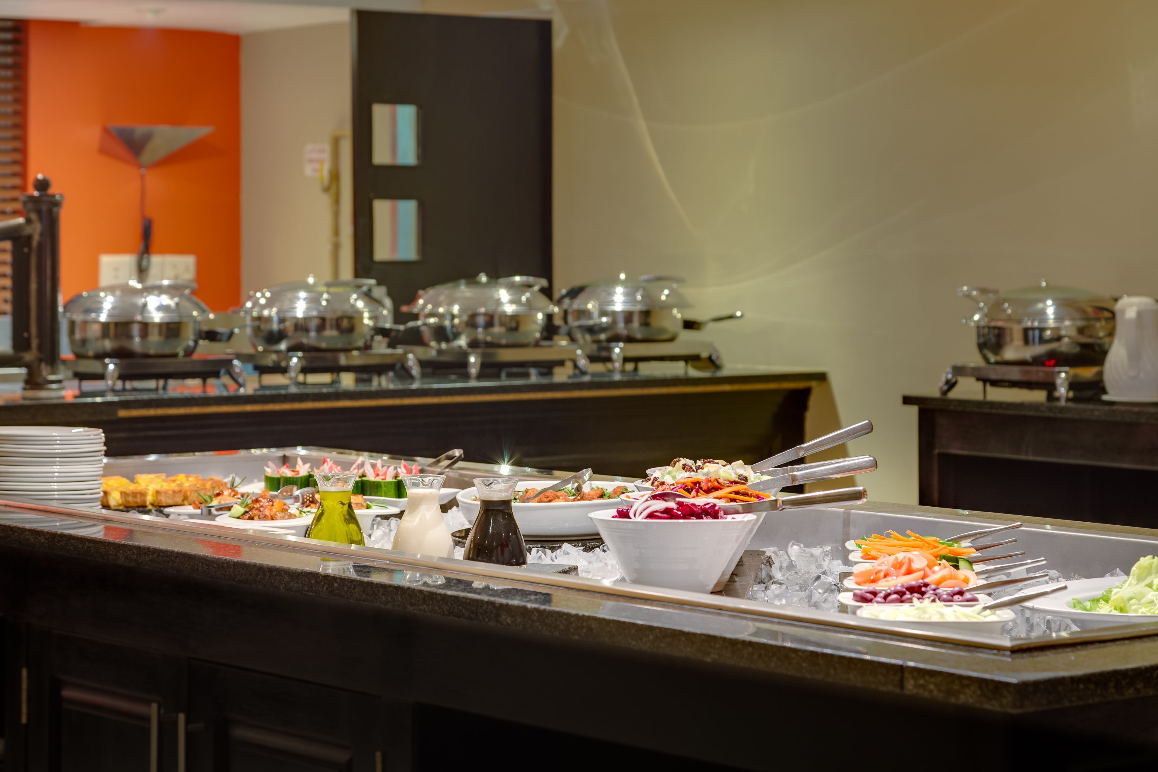 A buffet with various dishes, including salads, vegetables, and sauces.