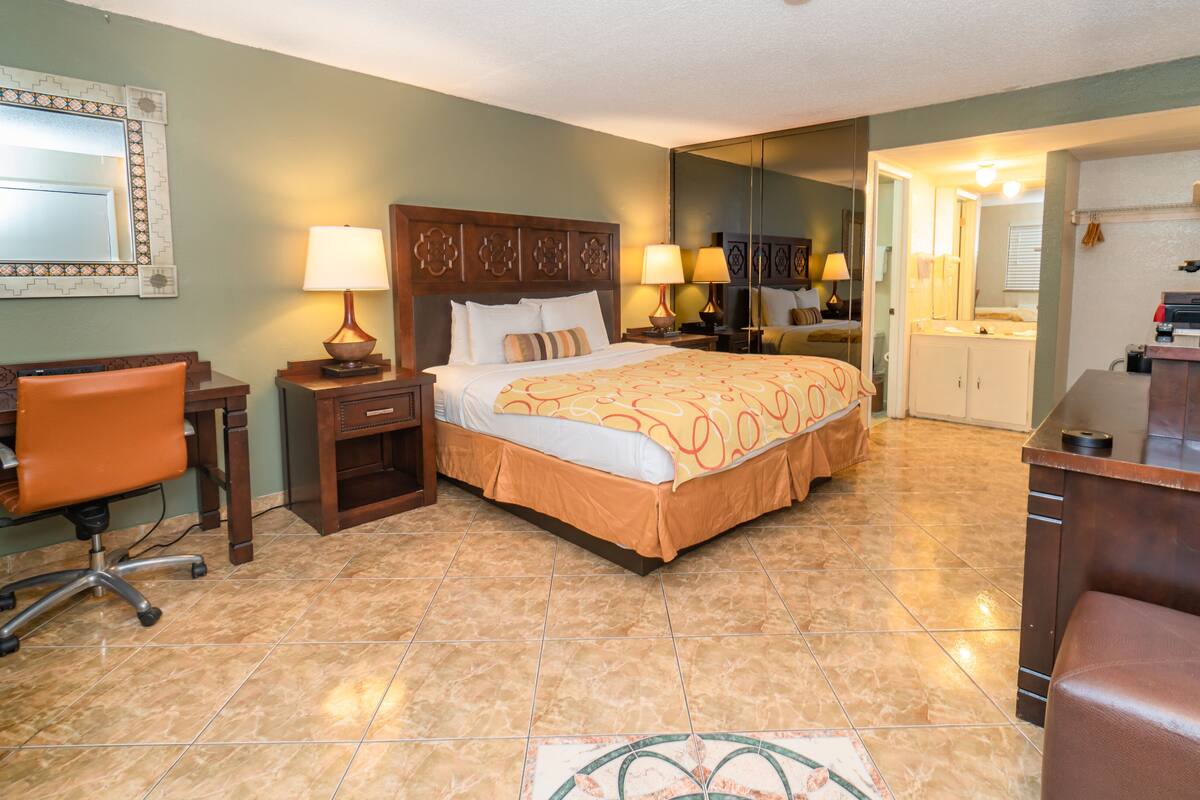A hotel room with a bed, desk, chair, and a bathroom visible through an open door.