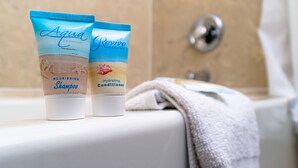 Two toiletry products, a nourishing shampoo and a hydrating conditioner, on a bathroom counter. - Sevilla Inn - Near Medieval Times (Kissimmee)