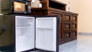 A compact refrigerator with a microwave on top, a wooden cabinet with drawers, and a tiled floor. - Sevilla Inn - Near Medieval Times (Kissimmee)