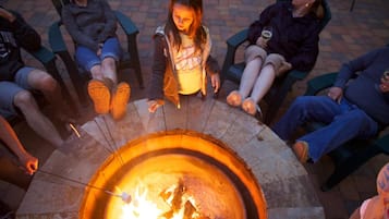 Eine Gruppe von Menschen sitzt um eine runde Feuerstelle im Freien.