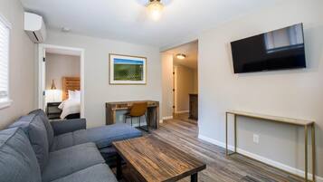 A modern living room with a gray sofa, wooden coffee table, and a TV mounted on the wall.
