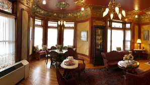 A room with a dining table, chairs, a sofa, a fireplace, and a chandelier. - Redstone Inn And Suites (Dubuque)