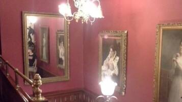 A room with a staircase, a chandelier, and multiple framed mirrors on the walls.