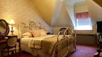 Un dormitorio con cama, escritorio, silla, espejo, ventana con cortinas y ventilador de techo.