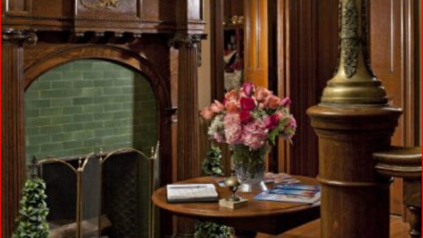 A room with a fireplace, a table with a vase of flowers, and a chandelier. - Whistling Swan Inn (Stanhope)