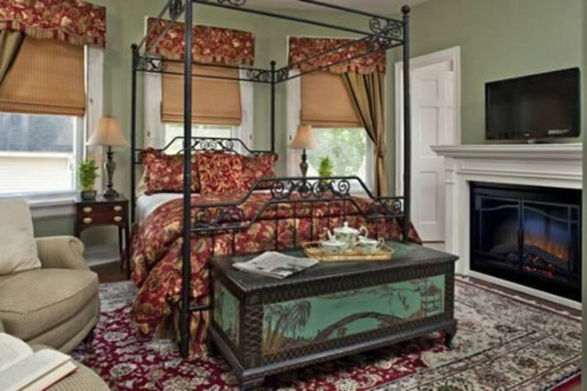A four-poster bed with floral bedding, a fireplace, and a television.