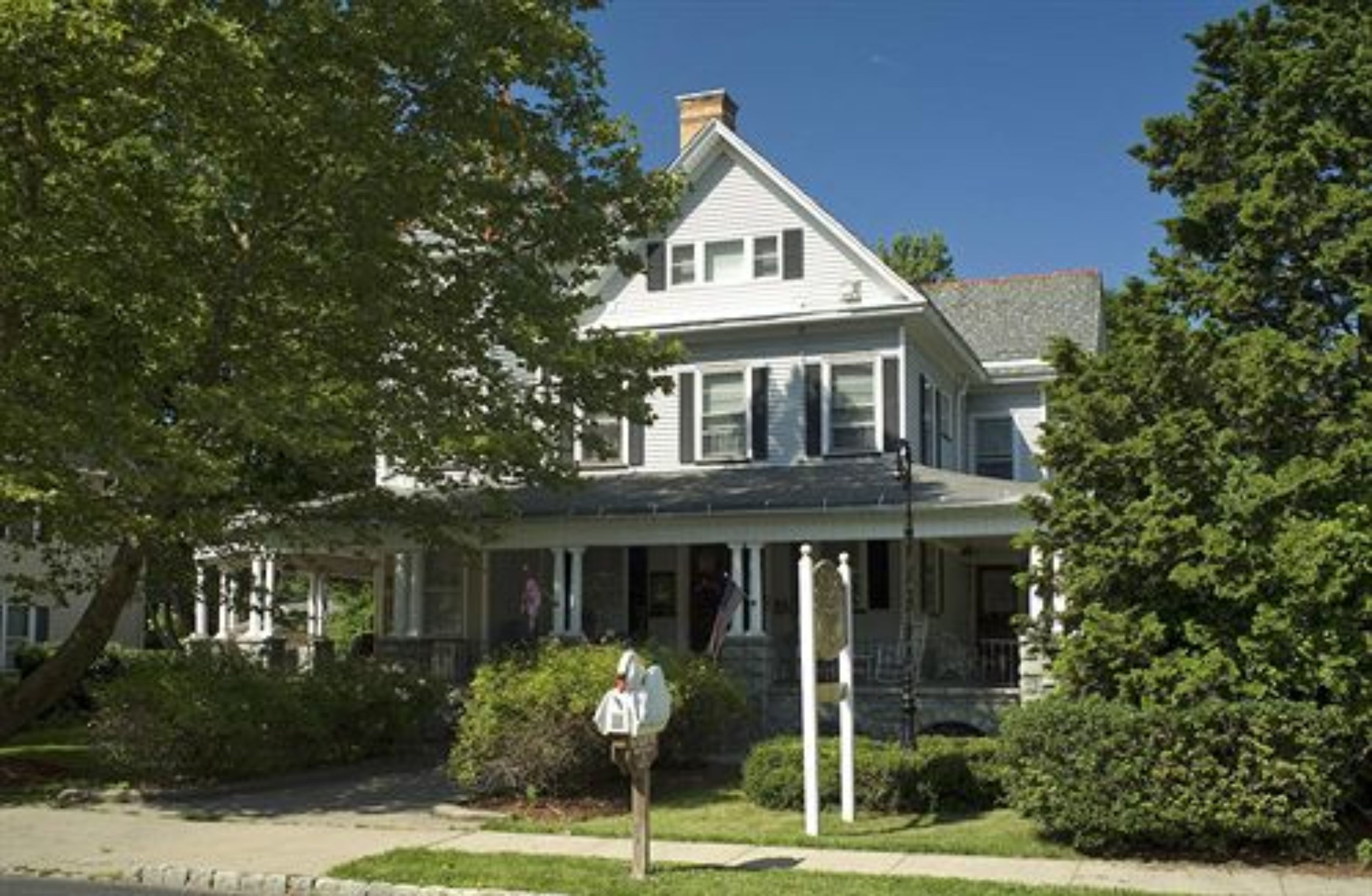 A two-story house with a porch, a chimney, and a mailbox.
