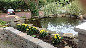 A garden with a pond, yellow flowers, and a stone wall. - Whistling Swan Inn (Stanhope)