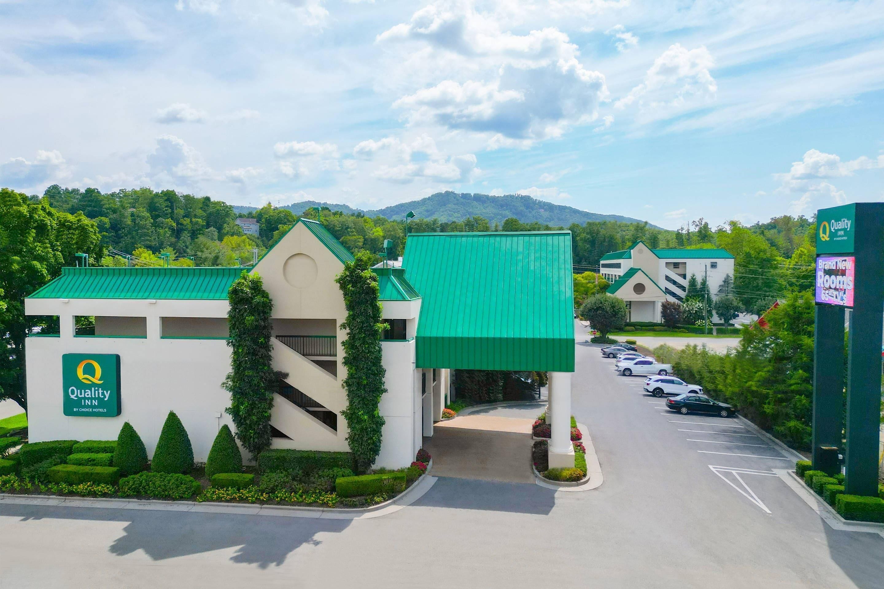 A hotel entrance with a green roof, a sign for Quality Inn by Choice Hotels, and a parking lot.