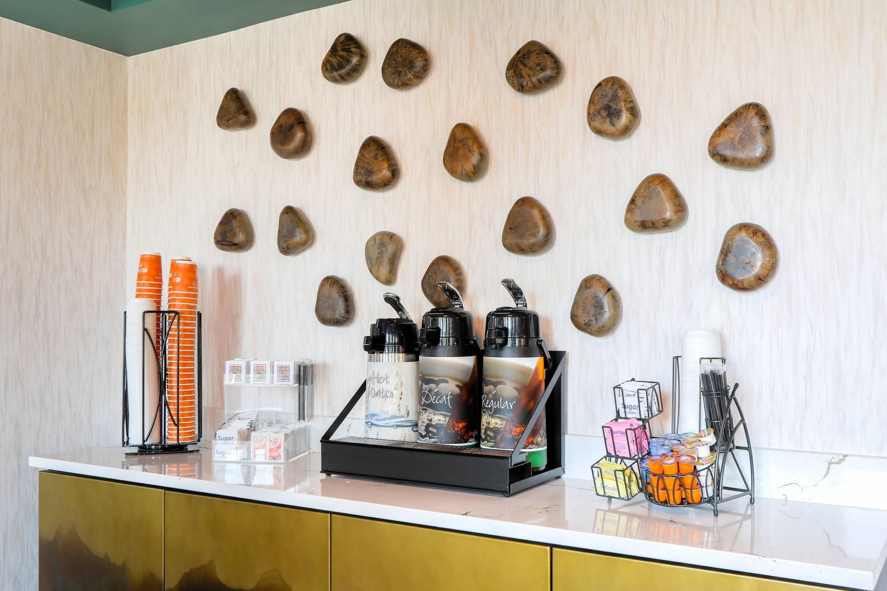 A counter with coffee dispensers, sugar packets, and a coffee machine.