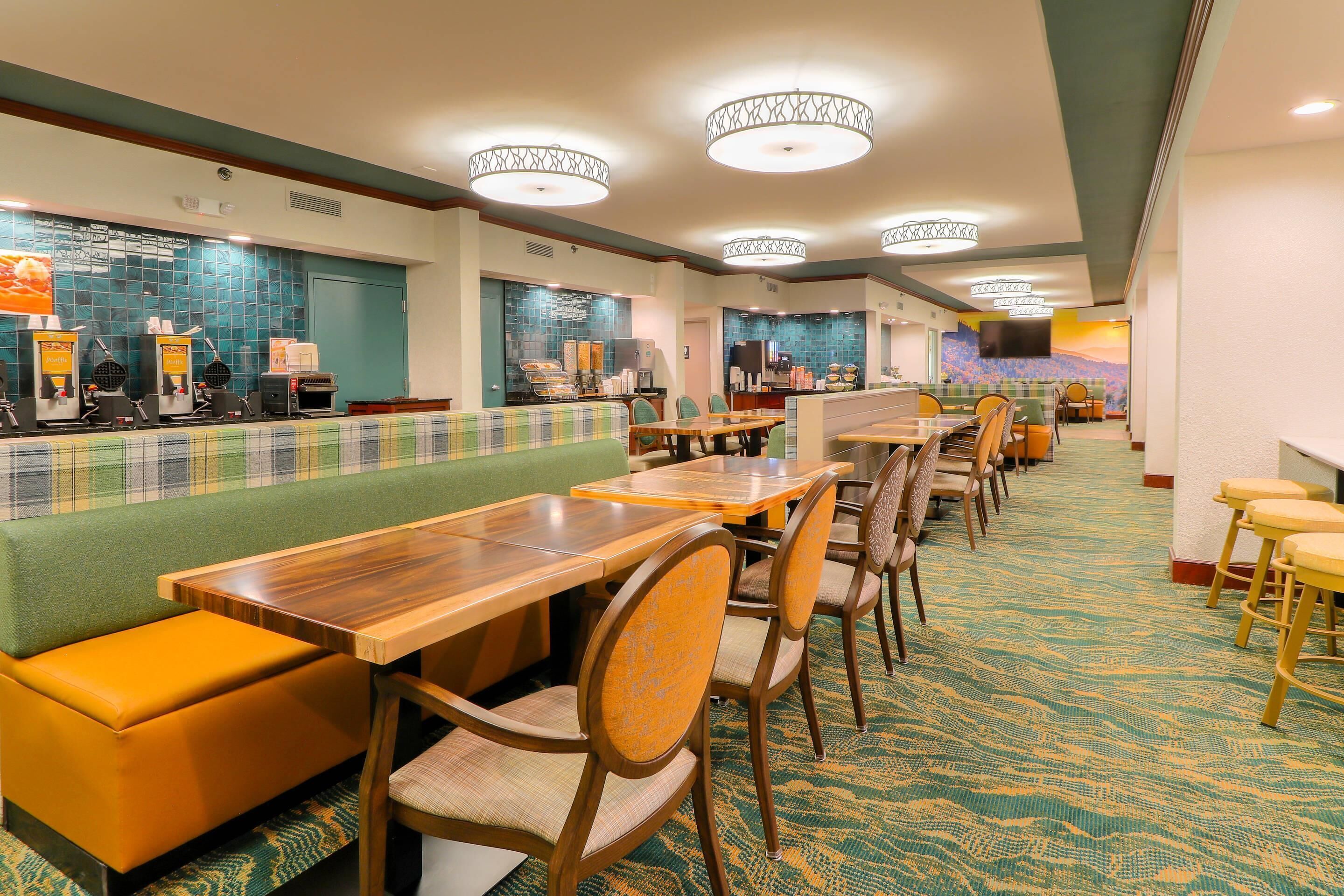 A hotel lobby with a long counter, seating area, and a television screen.