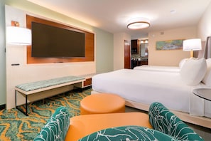 A hotel room with a large bed, a bench, a small table, and a television.