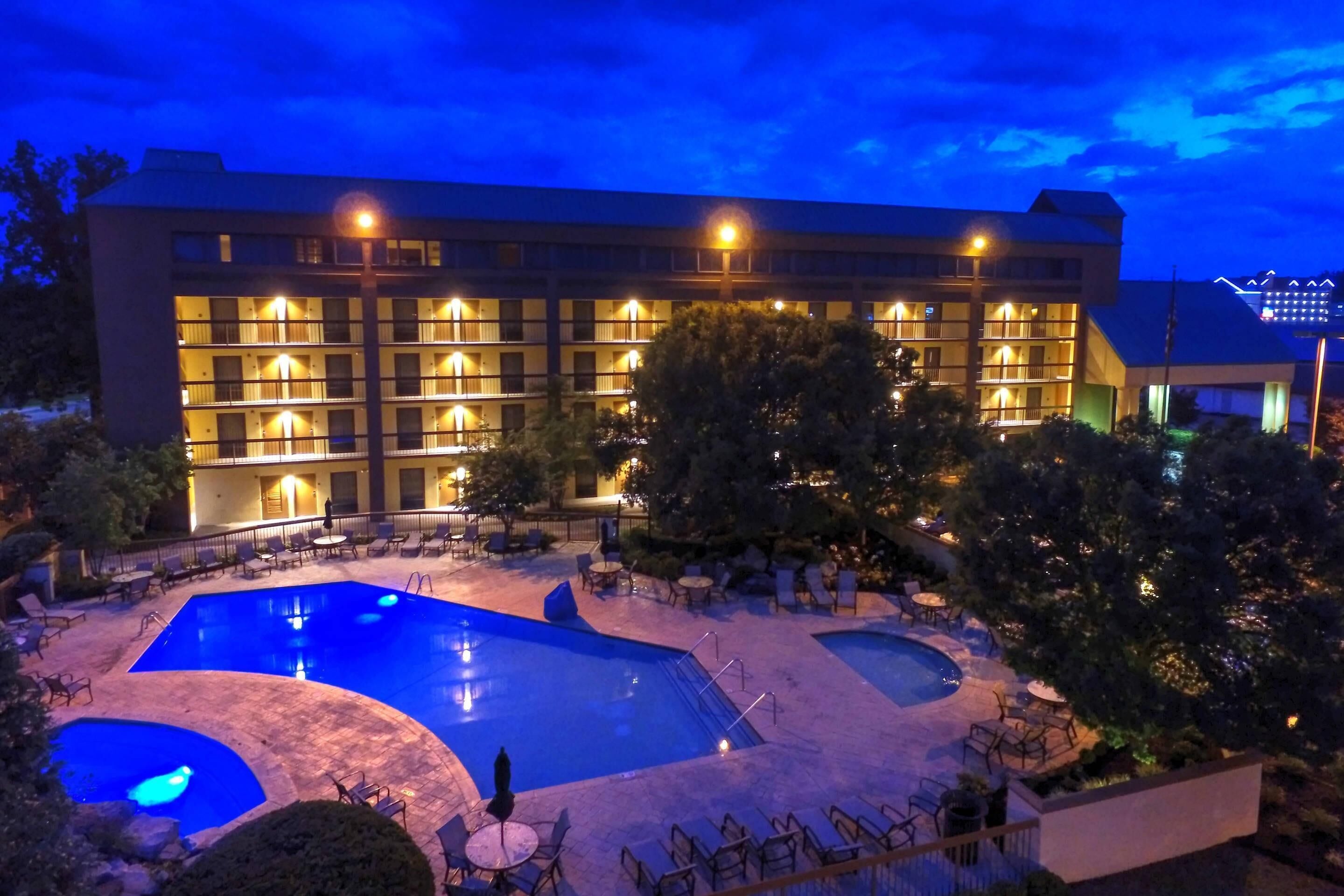 A hotel with multiple balconies, a swimming pool, and outdoor seating areas.