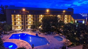 A hotel with multiple balconies, a swimming pool, and outdoor seating areas.