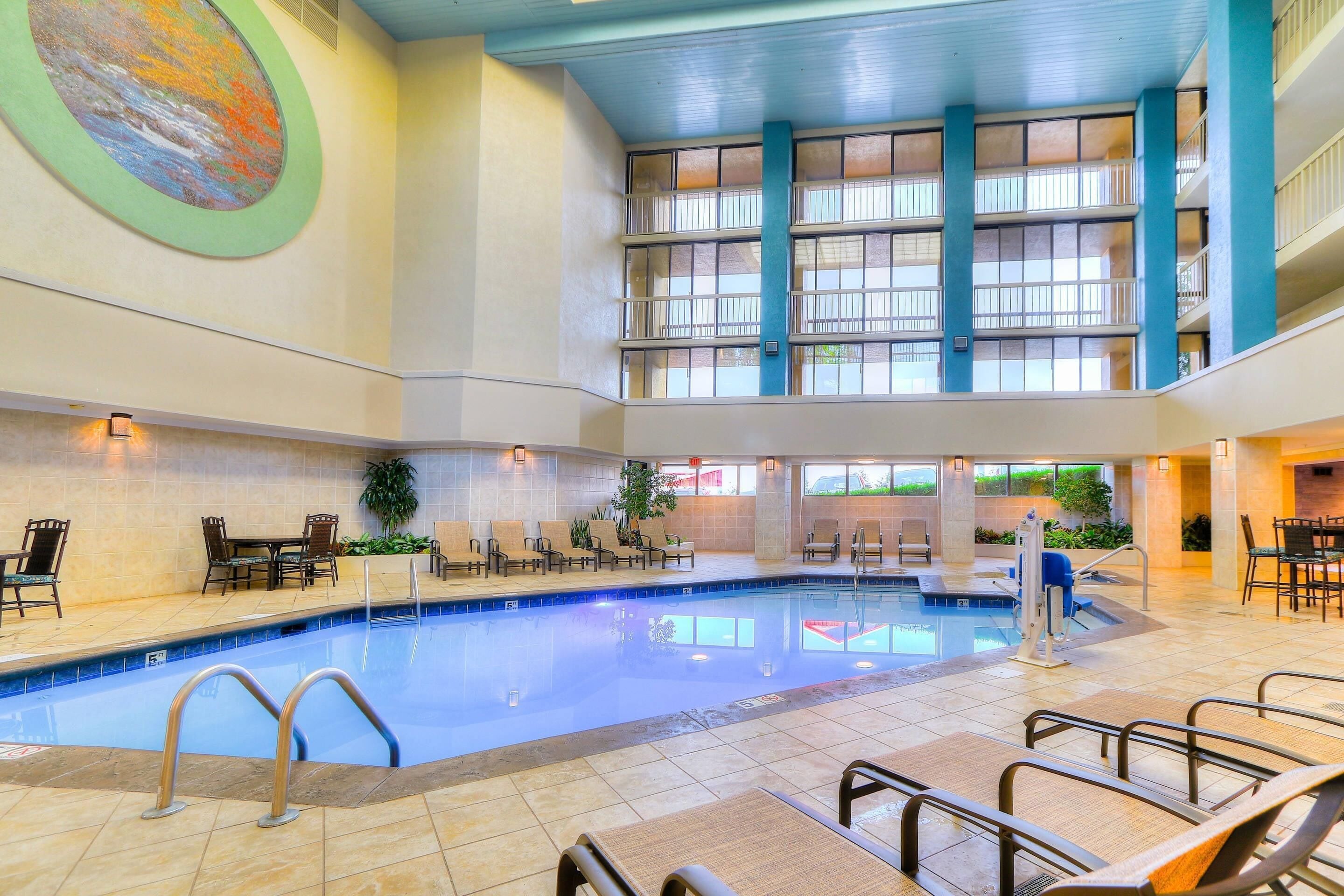 Una piscina interior con varios niveles, zonas de estar y un gran mural en la pared.