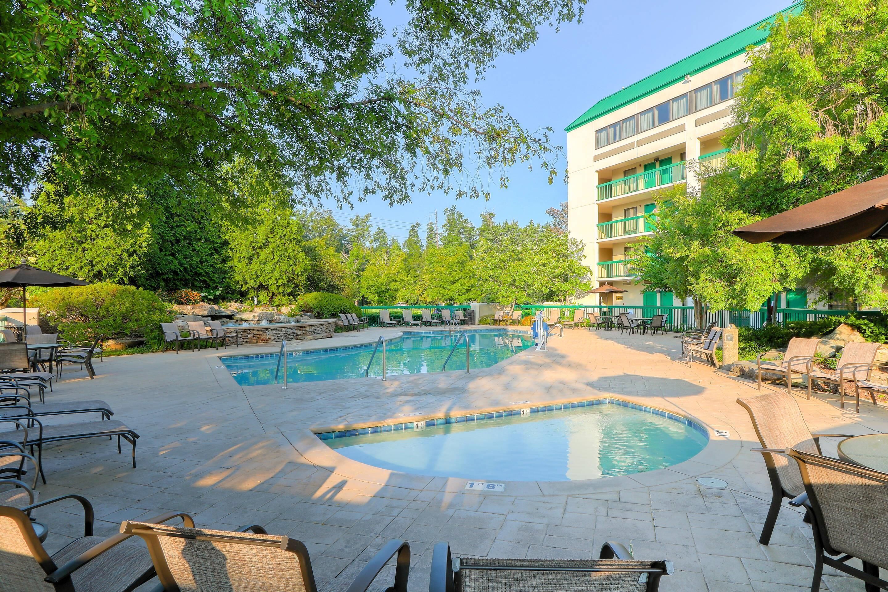 A pool area with lounge chairs and a building with balconies.