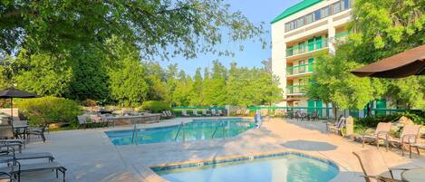 A pool area with lounge chairs and a building with balconies.