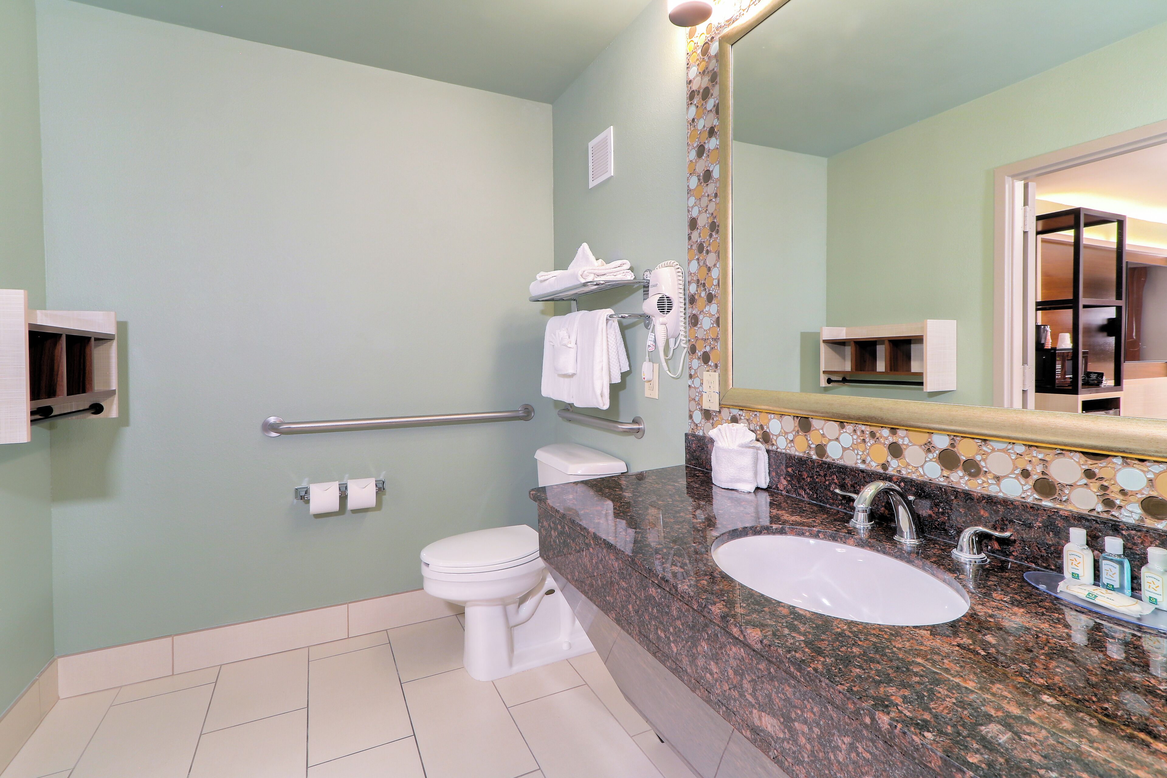 Un baño con inodoro, lavabo, toallero y secador de manos.