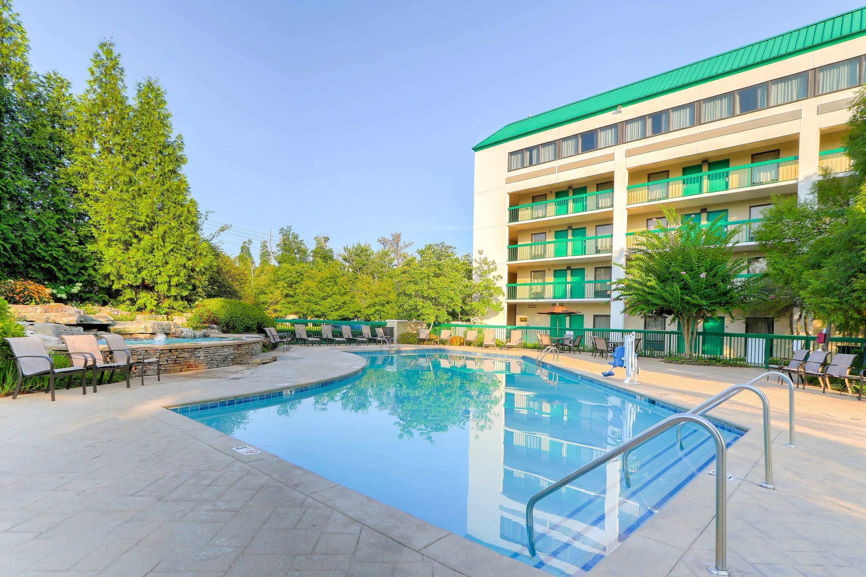 A hotel with a swimming pool, outdoor seating, and a multi-story building with balconies.