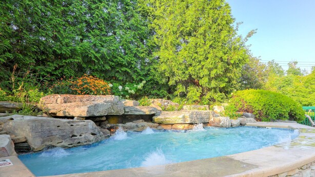 A hot tub surrounded by rocks and greenery. - Quality Inn Near the Island Pigeon Forge (Pigeon Forge)