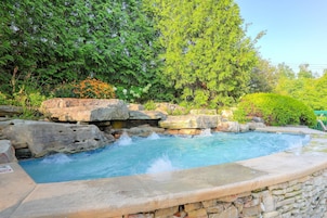 A hot tub surrounded by rocks and greenery.