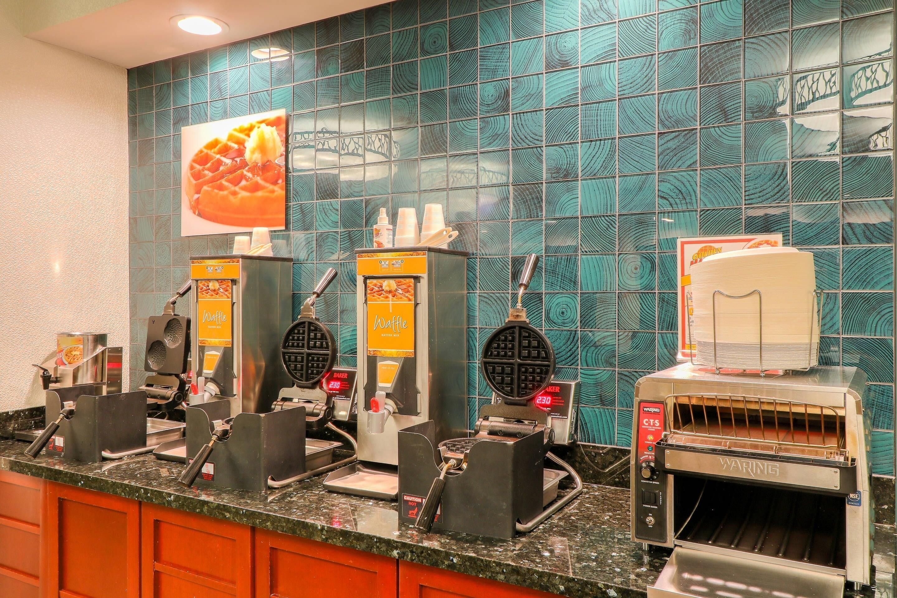 A waffle station with multiple waffle makers and a toaster oven.