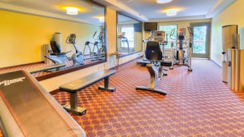 Un gimnasio con equipo de ejercicio, una banca y un espejo.