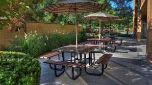 An outdoor patio area with picnic tables and striped umbrellas. - Quality Inn Near the Island Pigeon Forge (Pigeon Forge)