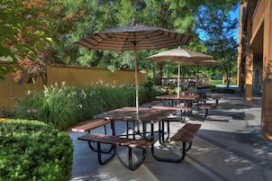 An outdoor patio area with picnic tables and striped umbrellas.
