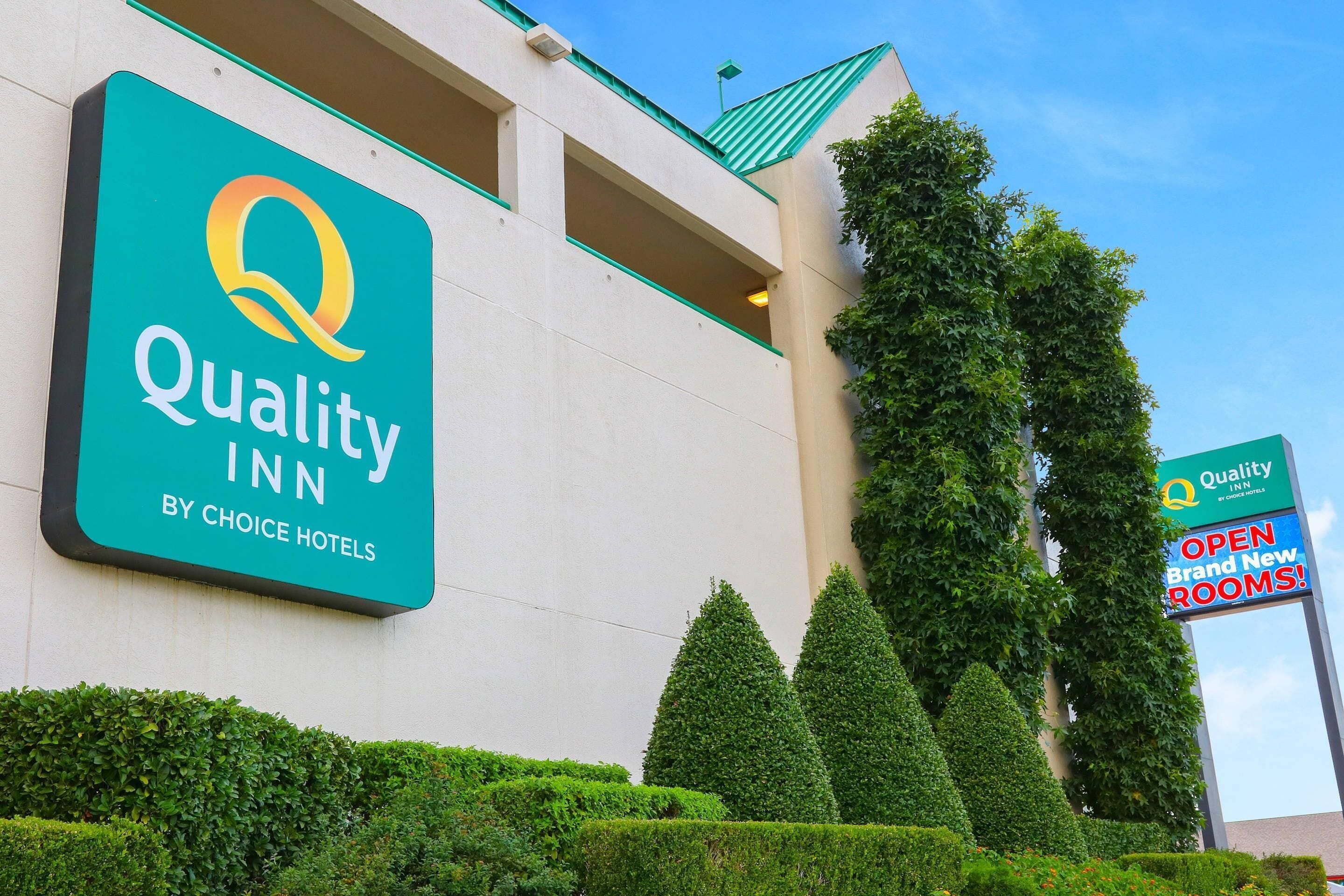 A Quality Inn sign, a building entrance, and a sign indicating new rooms are open.