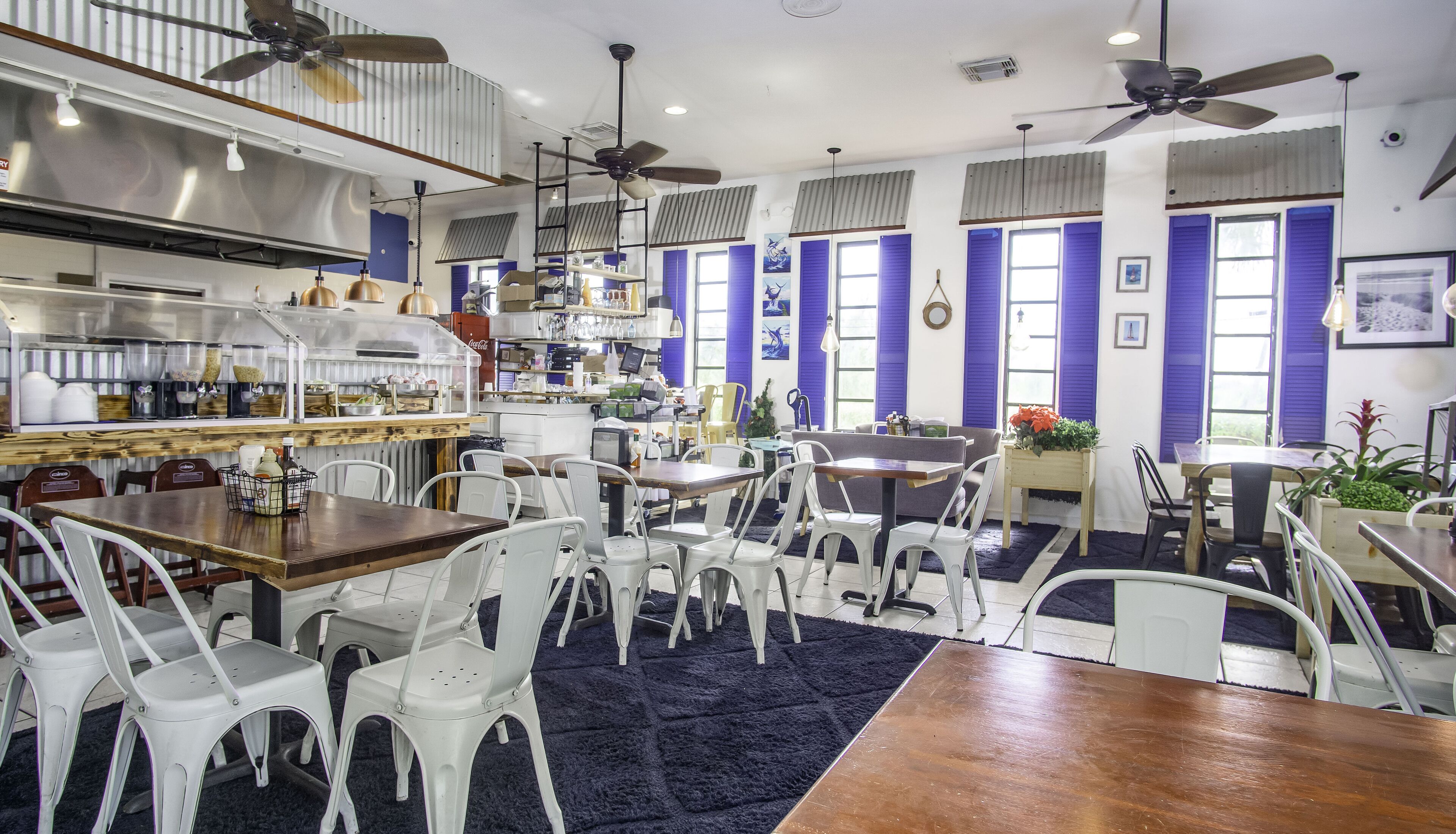 Een restaurant met een bar, meerdere plafondventilatoren en verschillende zitmogelijkheden, zoals tafels en stoelen.