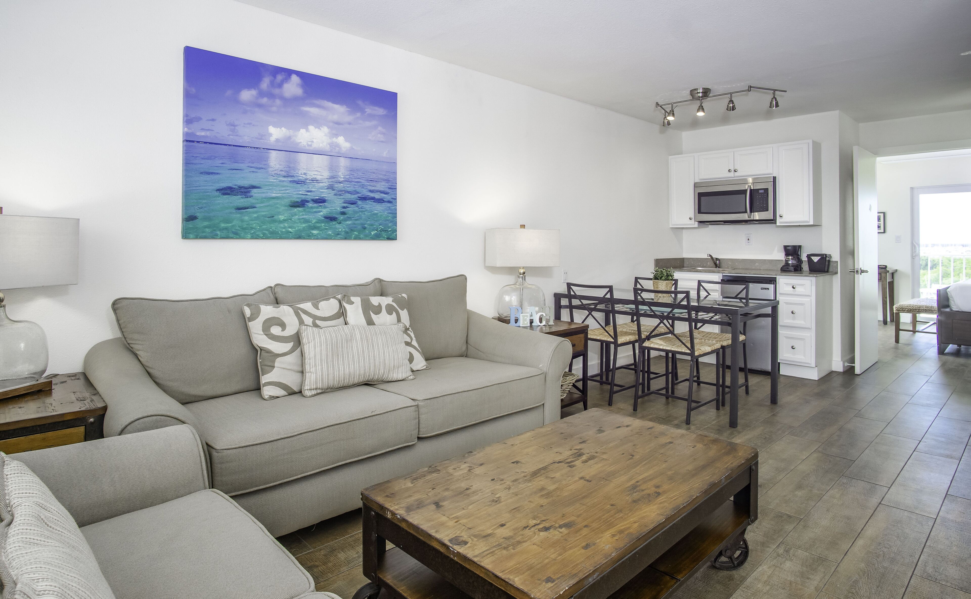 Una sala de estar con un sofá, una mesa de centro y un cuadro de una playa.