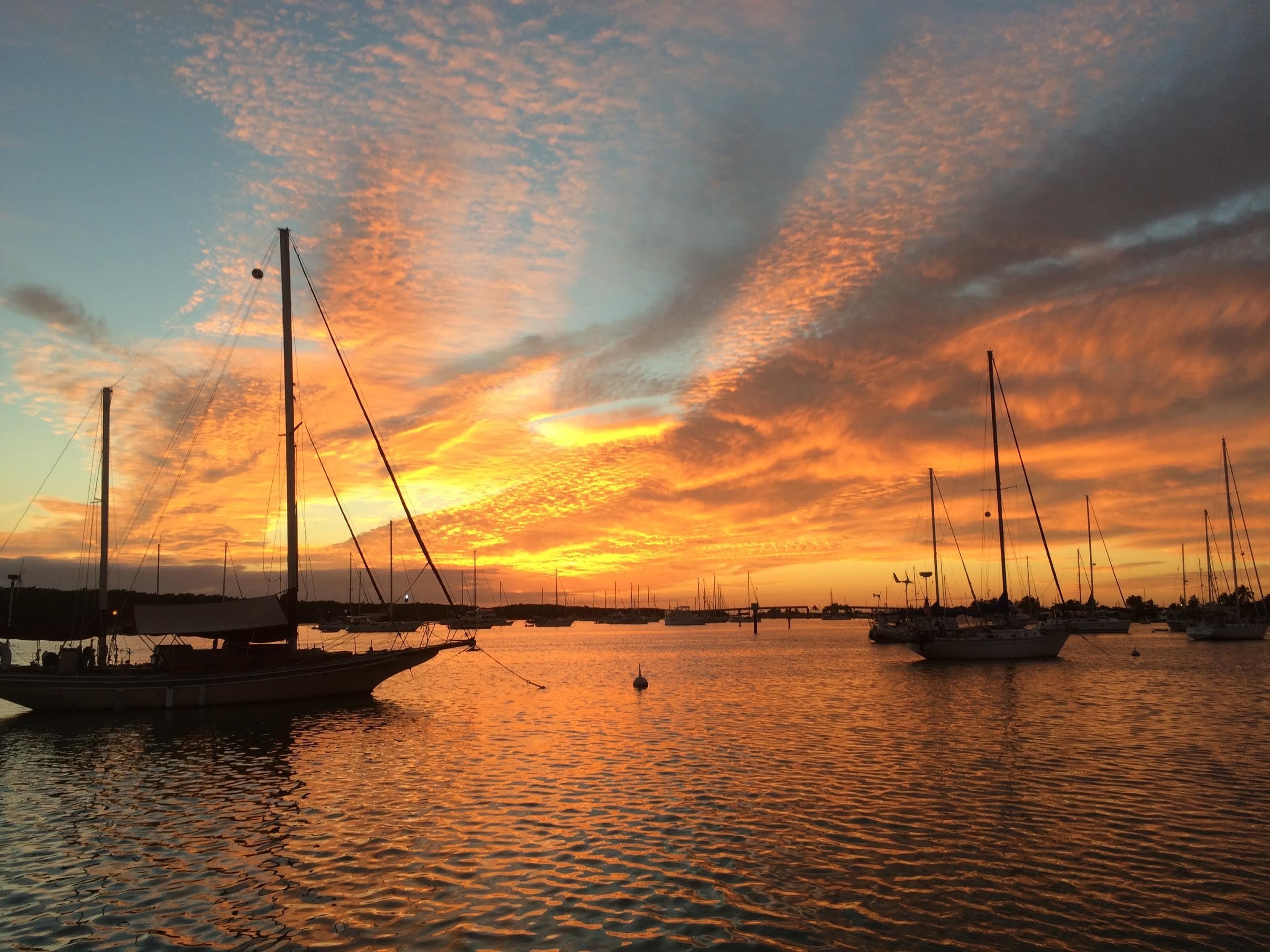 Un port de plaisance où des bateaux sont amarrés sous un ciel embrasé par le coucher du soleil.