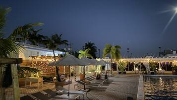 Een buitenzwembad, ligstoelen bij het zwembad