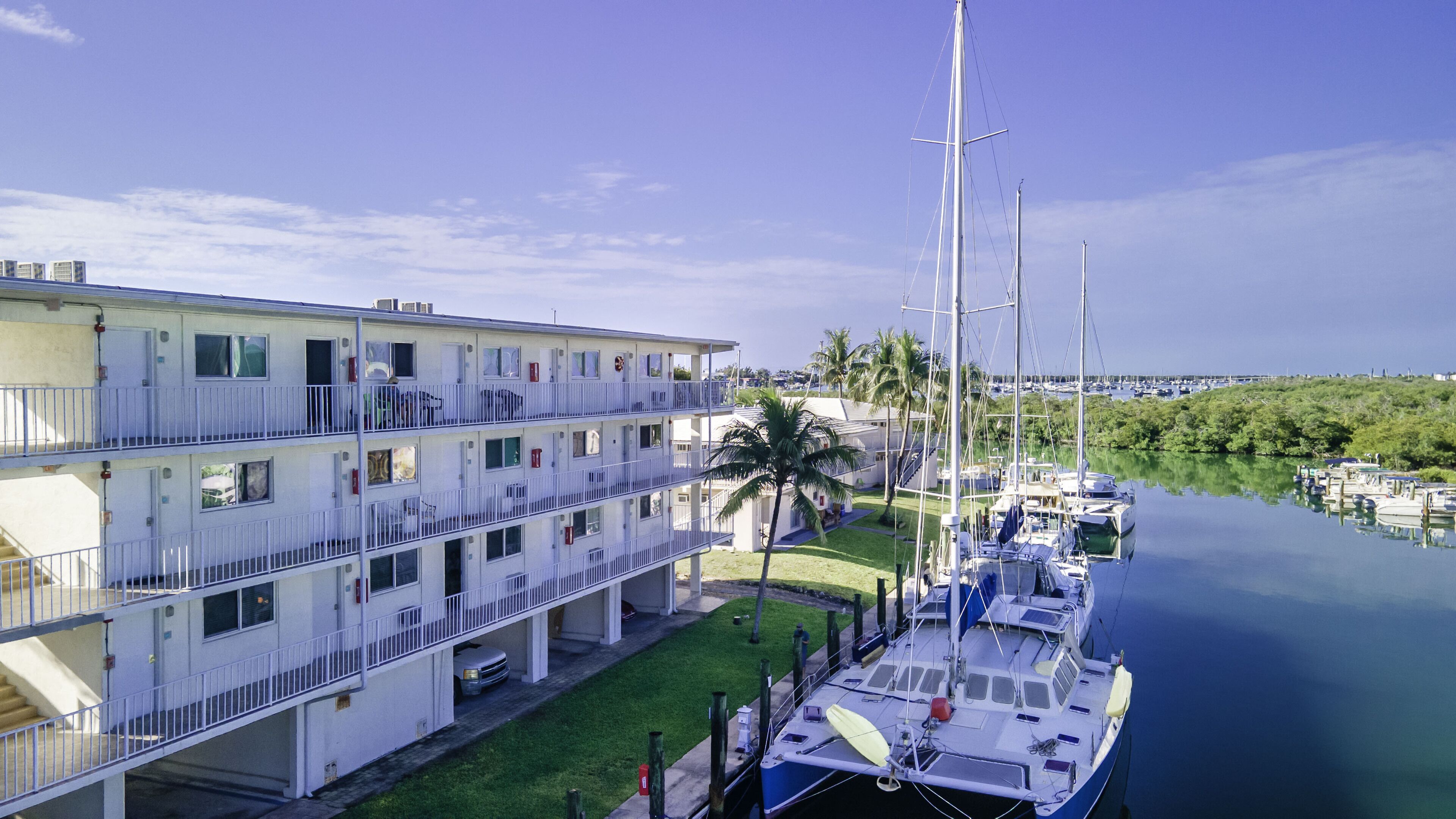 A multi-story hotel with balconies, a marina with boats, and a view of the water and distant buildings.
