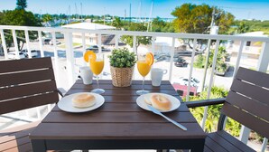 A table with breakfast items, a basket, and a view of a parking lot and buildings.