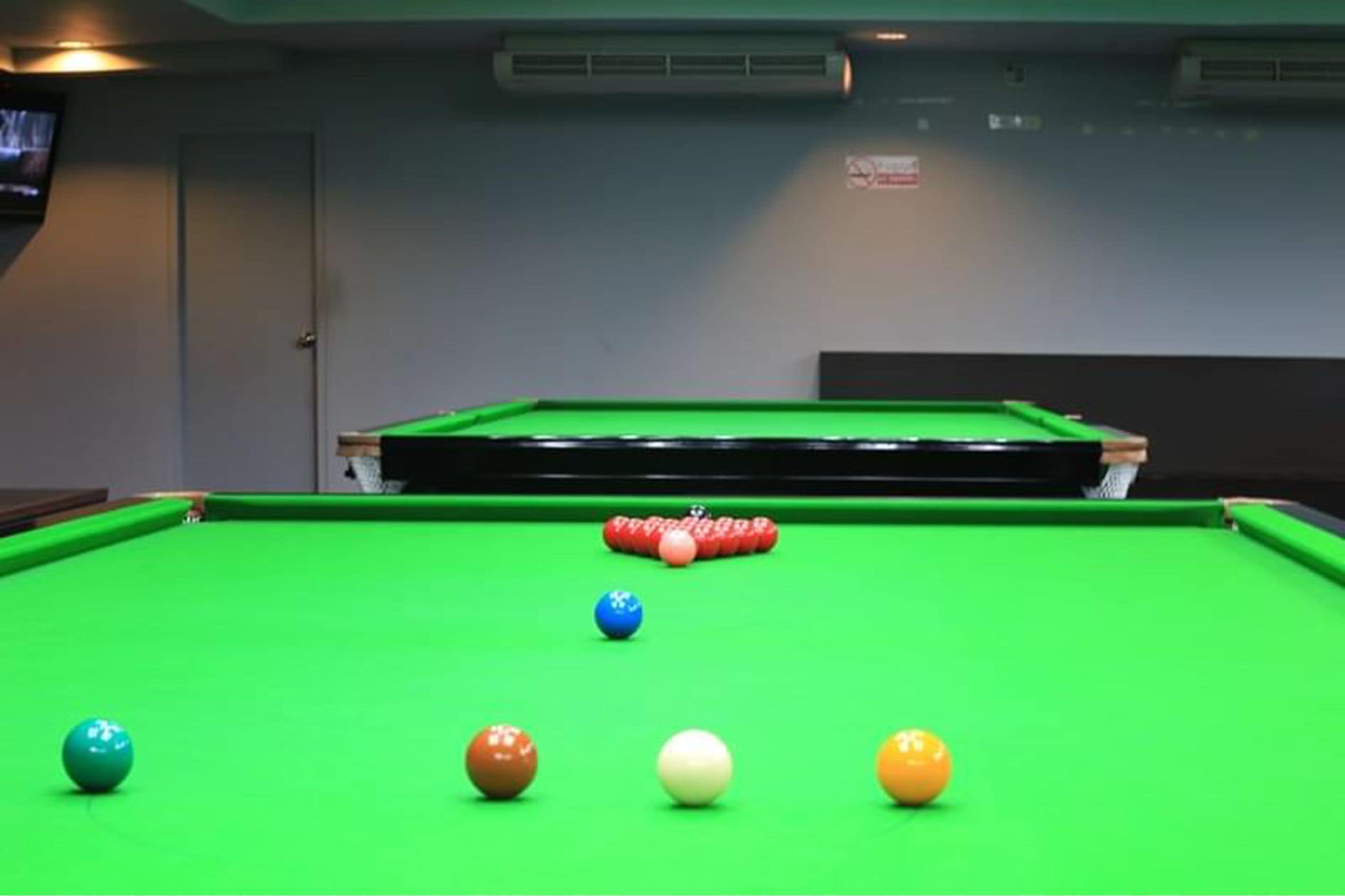 A pool table with balls in a room with a television and air conditioning unit on the wall.