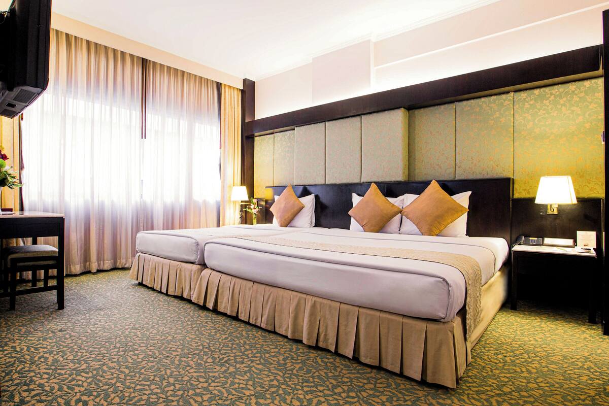 A hotel room with a large bed, two bedside tables, a desk, and a chair.