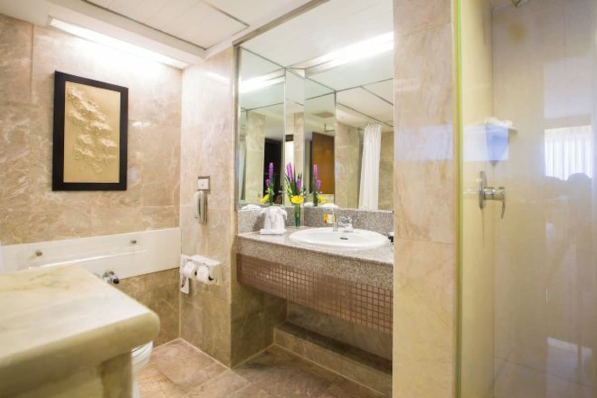 A bathroom with a marble wall, a framed picture, a sink, and a shower area.