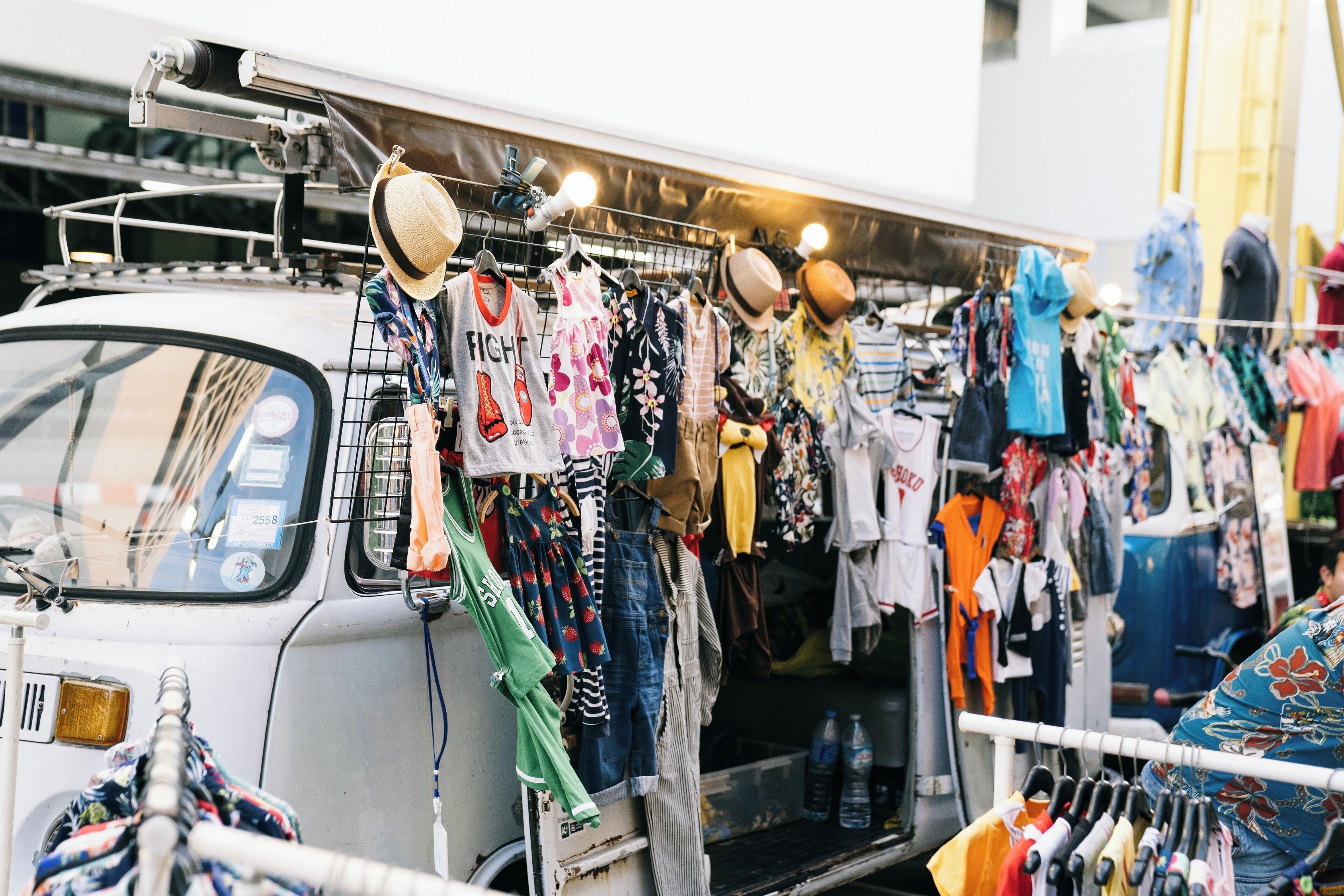 Un puesto de mercado con diferentes prendas de vestir exhibidas en estantes.