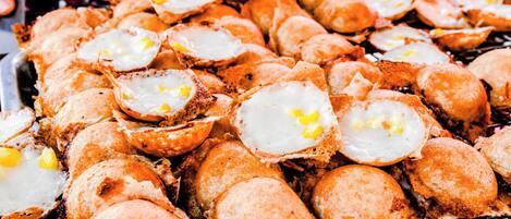 A grill with numerous round, breaded items topped with fried eggs.