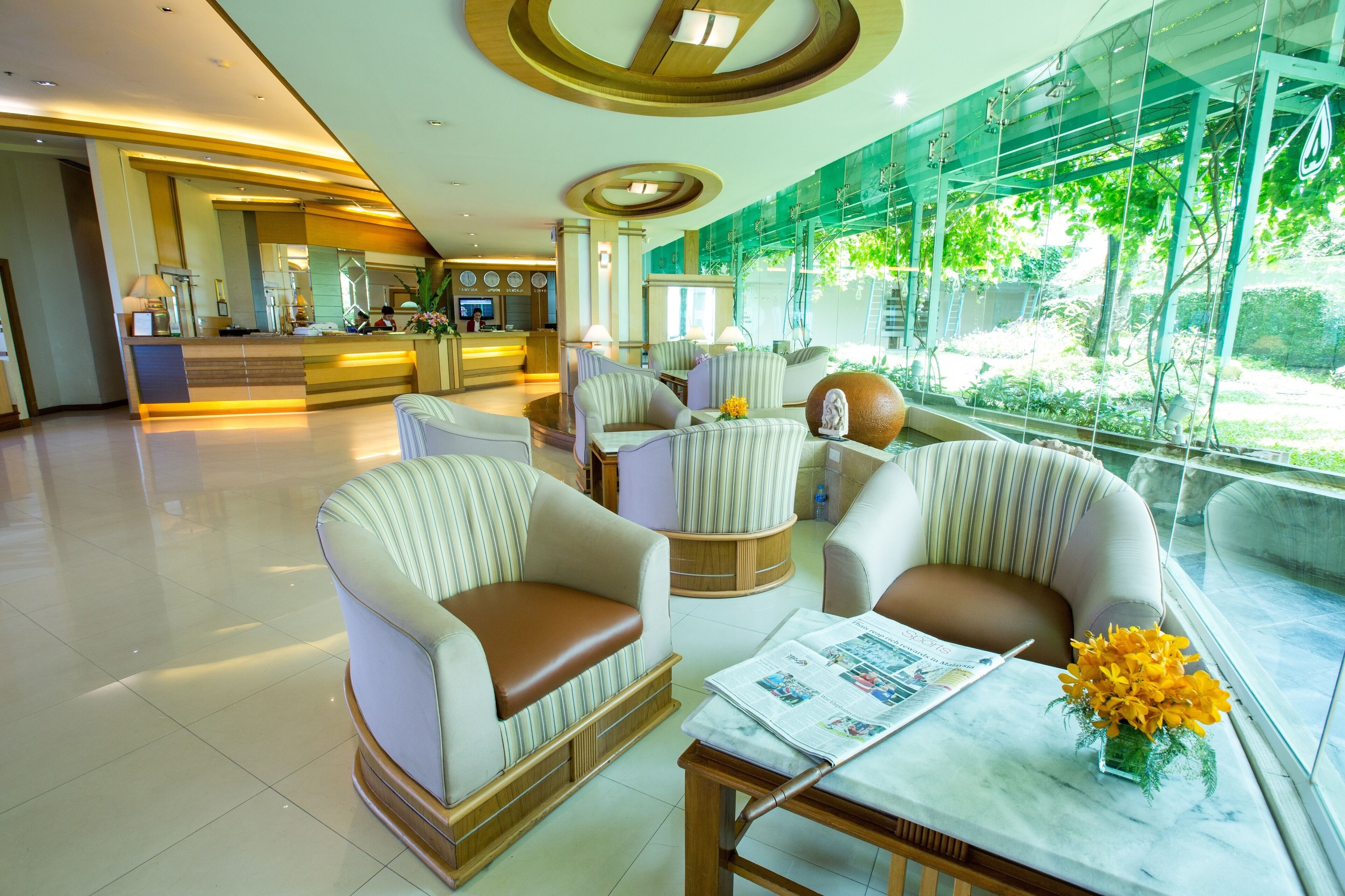 A spacious lobby with a reception desk, comfortable seating areas, and large windows offering a view of the outdoors.