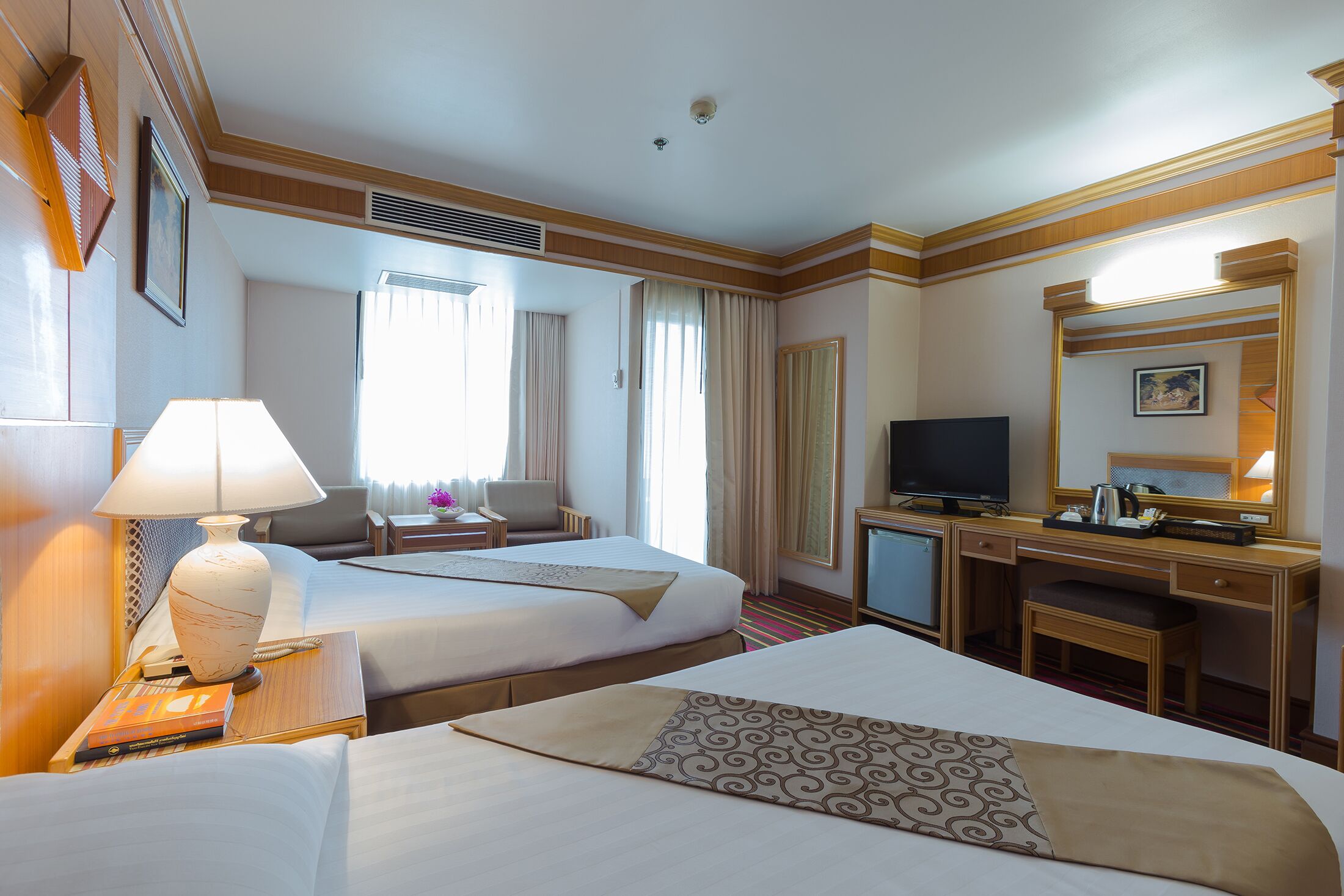 Une chambre d’hôtel avec deux lits, un bureau, une télévision et un miroir.